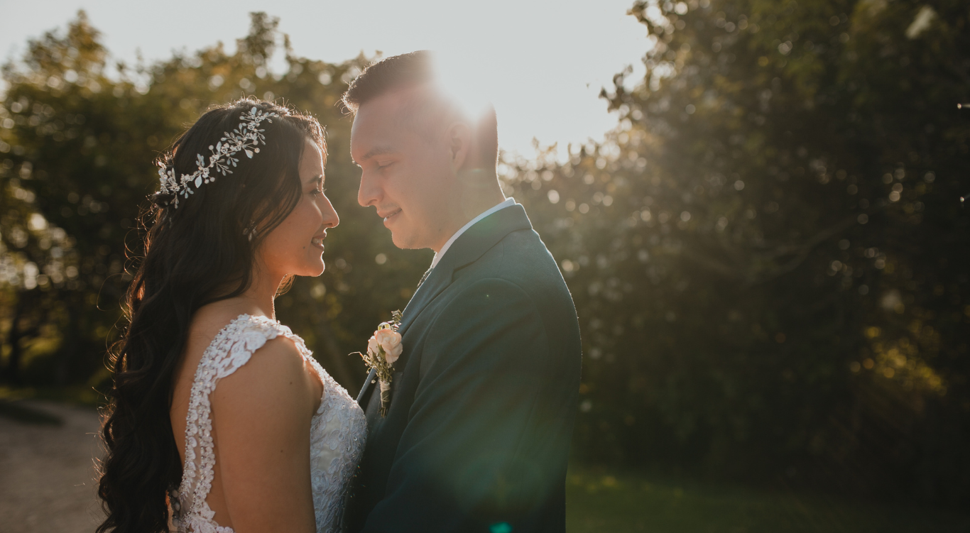 Novios mirándose al atardecer en entorno verde
