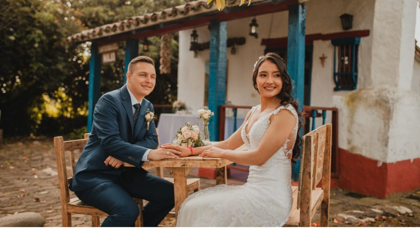 Novios tomados de la mano en mesa al aire libre