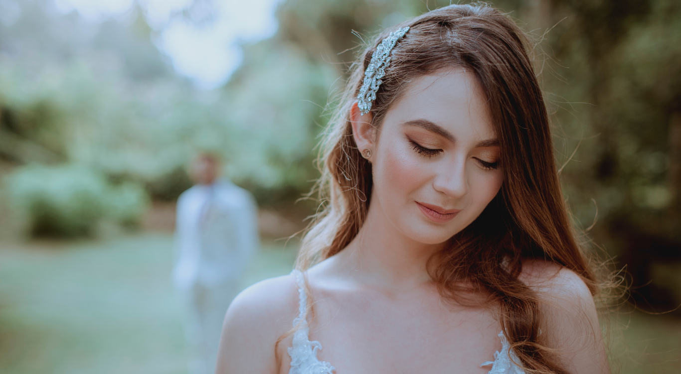 Novia en jardín con novio al fondo
